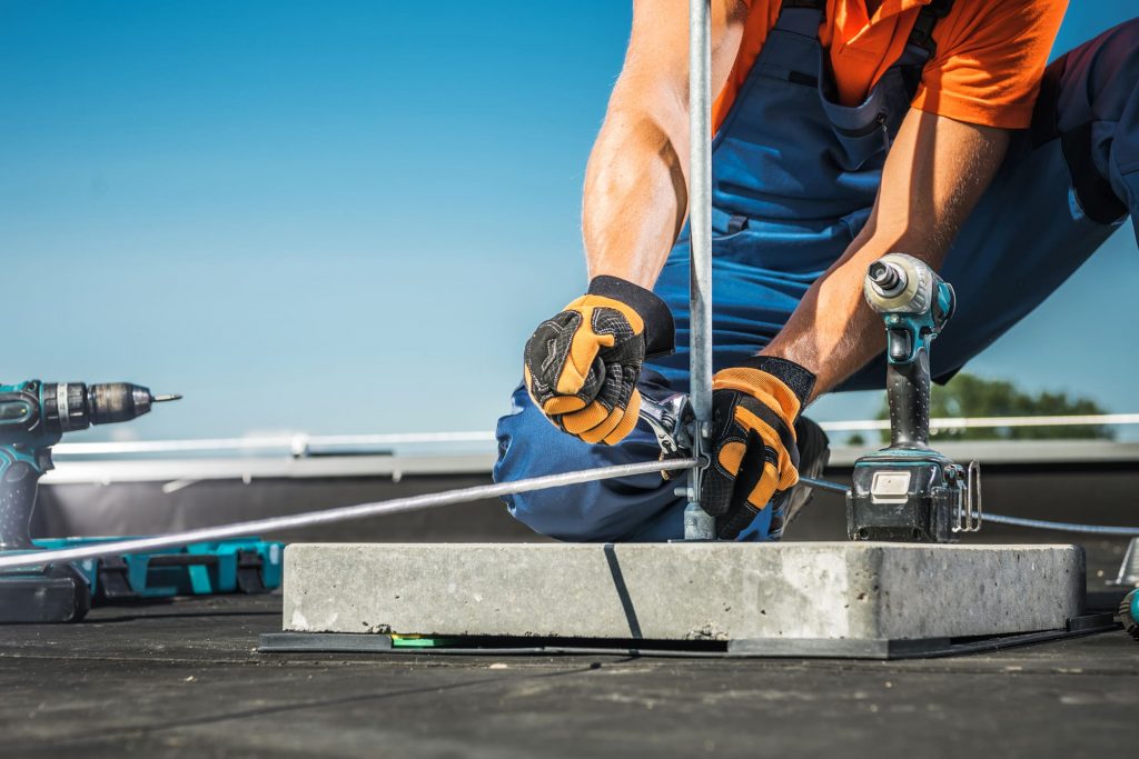 Fachtechniker von Hans Elektrotechnik montiert Blitzschutzableiter auf Dach an klaren Sonnentag